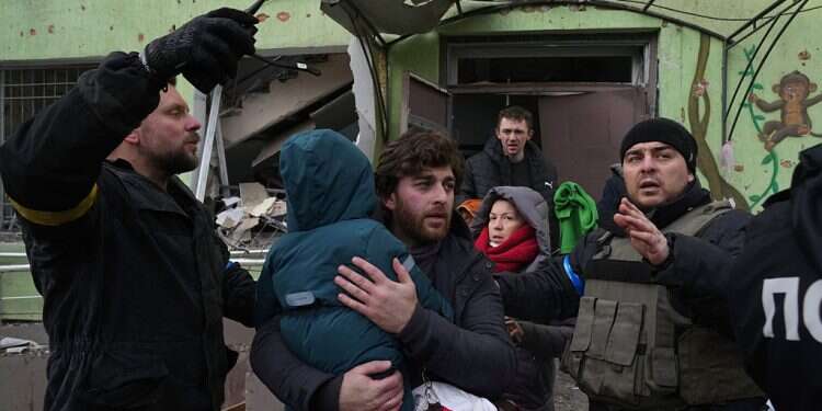 A man carries his child away from a damaged maternity hospital in Mariupol, Ukraine, Wednesday, March 9, 2022 Escaping Ukraine, as a journalist