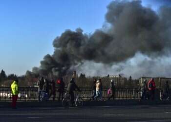 People walk as a cloud of smoke billows after an explosion near the airport in Lviv, western Ukraine,, on March 18, 2022
Missiles hitting closer to central Lviv, Poland backs NATO peacekeeping mission