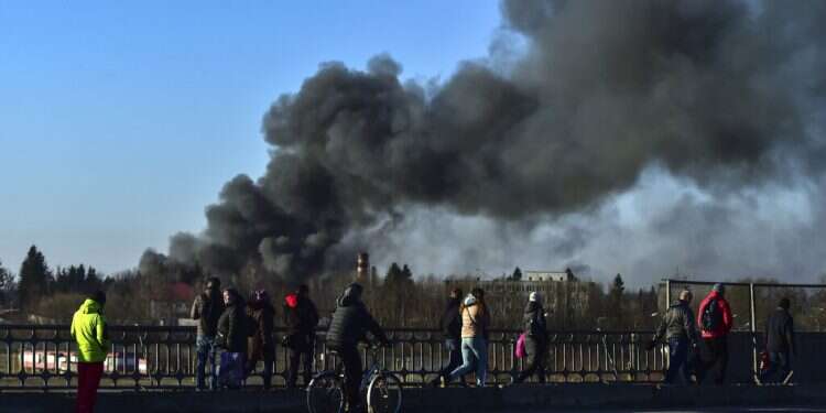 People walk as a cloud of smoke billows after an explosion near the airport in Lviv, western Ukraine,, on March 18, 2022
Missiles hitting closer to central Lviv, Poland backs NATO peacekeeping mission