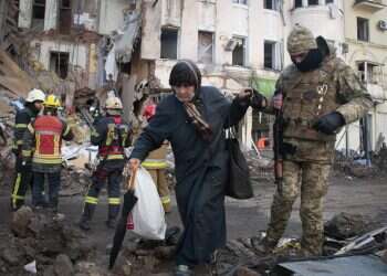 A volunteer of the Ukrainian Territorial Defense Forces assists a woman to cross the street in Kharkiv, Ukraine, March 16, 2022 Bombed Mariupol theater 'withstood impact' of attack, evacuation underway
