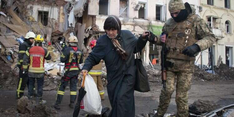 A volunteer of the Ukrainian Territorial Defense Forces assists a woman to cross the street in Kharkiv, Ukraine, March 16, 2022 Bombed Mariupol theater 'withstood impact' of attack, evacuation underway