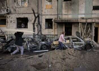 People carry wooden boards to cover the windows of a building damaged by a bombing the previous day in Kyiv, March 21, 2022 Ukrainian forces holding Mariupol, Zelenskyy reports 'step by step' progress in talks
