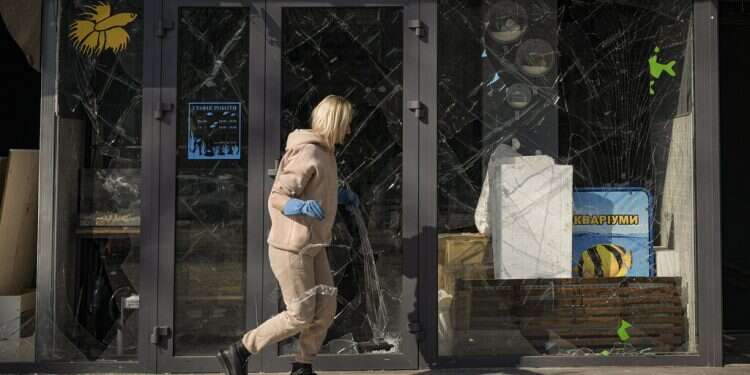 A woman removes pieces of broken glass from a shop window after a bombing in Kyiv on March 23, 2022
War causes 45% hit to Ukraine economy