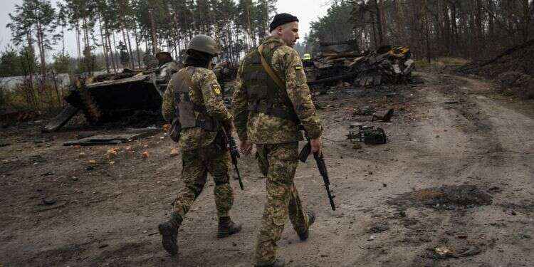 Ukrainian soldiers walk next to destroyed Russian tanks on the outskirts of Kyiv, March 31, 2022 Zelenskyy warns Russian withdrawals a tactic to build up forces elsewhere