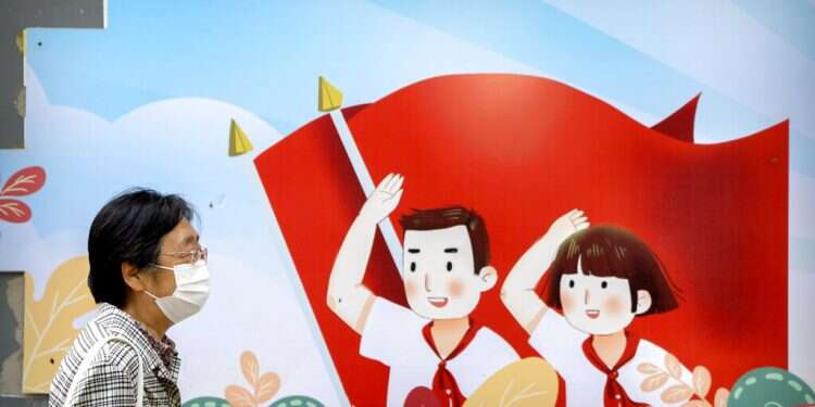 A woman wearing a face mask walks past a mural in Beijing, May 18, 2022 WHO: China's zero-COVID strategy not sustainable way to exit pandemic