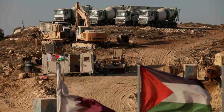 Construction trust are seen behind a Palestinian flag at the site for the Palestinian urban project Rawabi in the village of Atara, near Ramallah, on Dec. 29, 2010 Israel takes steps to 'build trust' with Palestinians ahead of Biden visit