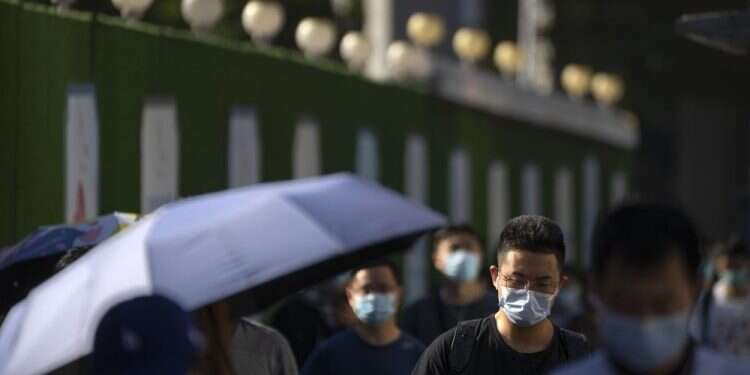Commuters wearing face masks walk along a street in the central business district in Beijing, Sept. 1, 2022 China locks down 21 million in Chengdu in COVID outbreak