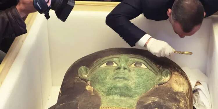 Mostafa Waziri, top official at the Supreme Council of Antiquities, takes a look with a magnifier at an ancient wooden sarcophagus during a handover ceremony at the foreign ministry in Cairo, Egypt, Jan. 2, 2023 Looted ancient sarcophagus returned to Egypt
