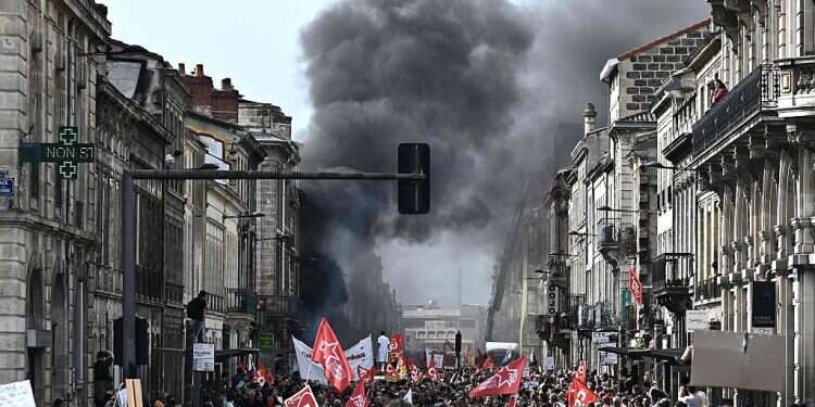 Smoke rises in the sky as protesters take part in a demonstration on a national action day, a week after the government pushed a pensions reform through parliament without a vote Protesters, police clash across France in day of strife over Macron's pension changes