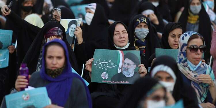 A supporter of presidential candidate Ebrahim Raisi holds a poster of him during an election rally in Tehran, Iran June 14, 2021 Iran's president orders probe of poisoning at girls' schools