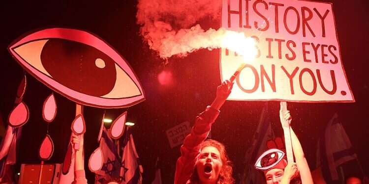 Demonstrators lift placards and use flares during a rally to protest the government's judicial reform bill, Tel Aviv, April 29, 2023 Israelis rally against judicial reform for 17th consecutive week