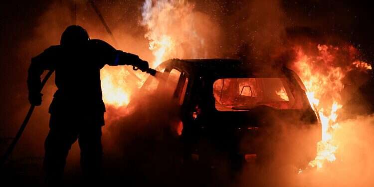 A French firefighter works to extinguish a burning car during the fifth day of protests following the death of Nahel, a 17-year-old teenager killed by a French police officer in Nanterre , July 2, 2023 5th night of unrest quieter in France amid massive police deployment