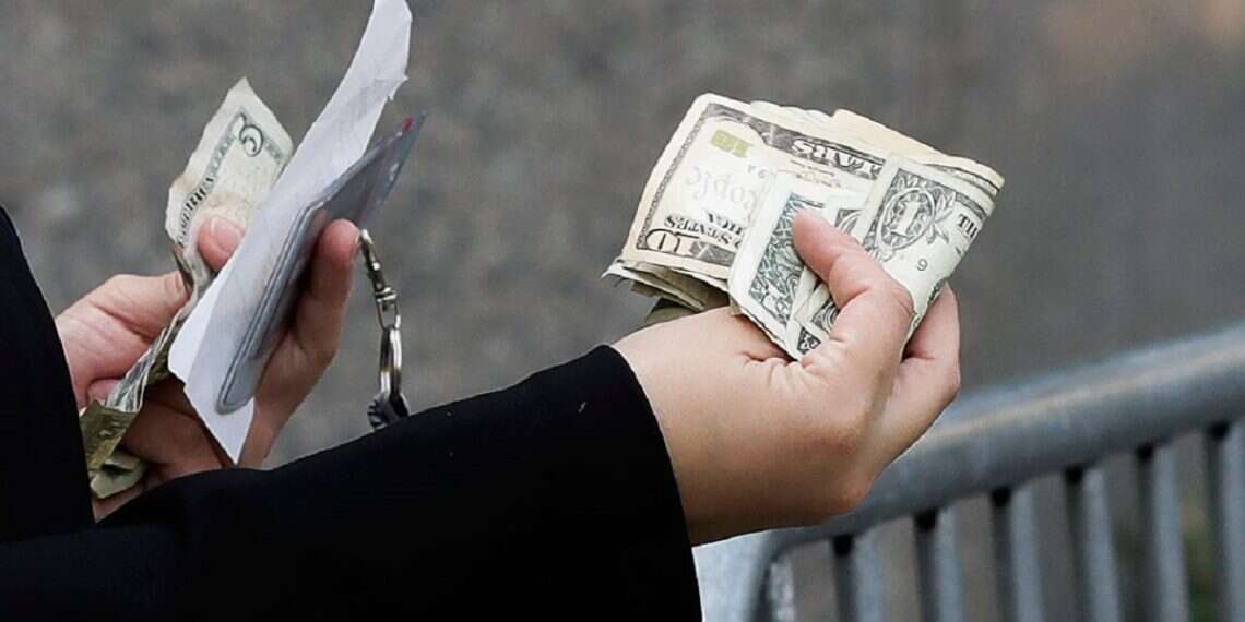 A woman pays with cash as she buys from a street vendor, Sept. 26, 2017 in New York Stay financially literate: A short quiz to test your knowledge