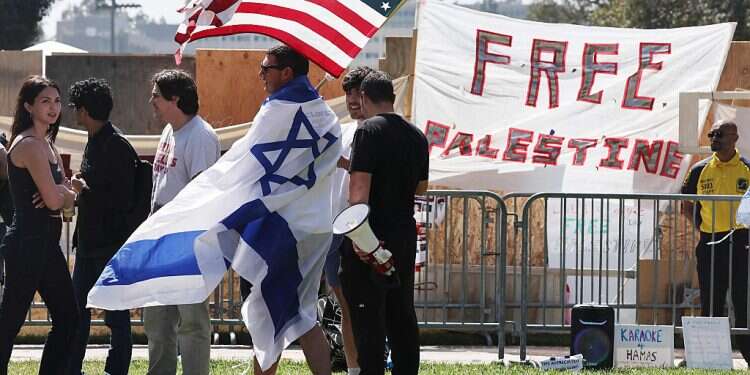 A counter-demonstrator wears an Israeli flag while carrying an American flag near a pro-Palestinian encampment at the UCLA, April 30, 2024 in Los Angeles, California Violent clashes between Israel supporters, pro-Palestinian protesters at UCLA