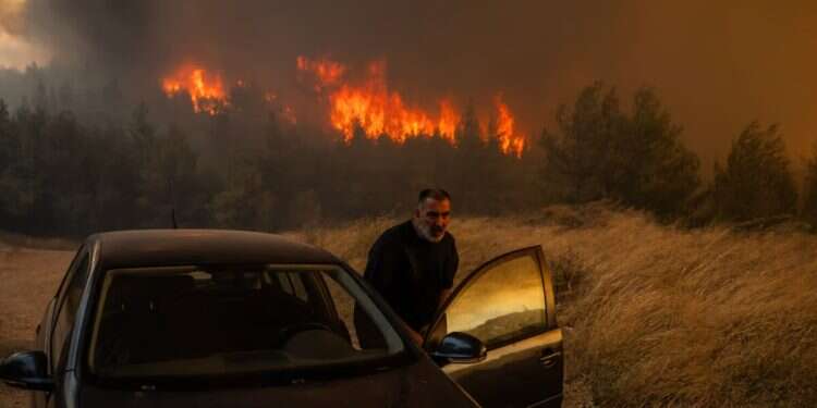 A resident quickly gets into his vehicle to escape the wildfire in Dione