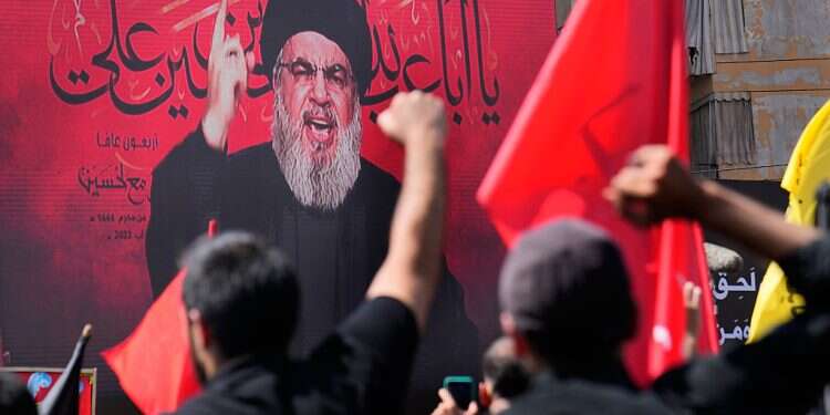 The now-eliminated Hezbollah leader Sheik Hassan Nasrallah speaks via a video link, as his supporters raise their hands, during the Shiite holy day of Ashoura, in the southern suburb of Beirut, Lebanon, in Beirut, Lebanon, Tuesday, Aug. 9, 2022 Hassan Nasrallah: Who was the terrorist mastermind?