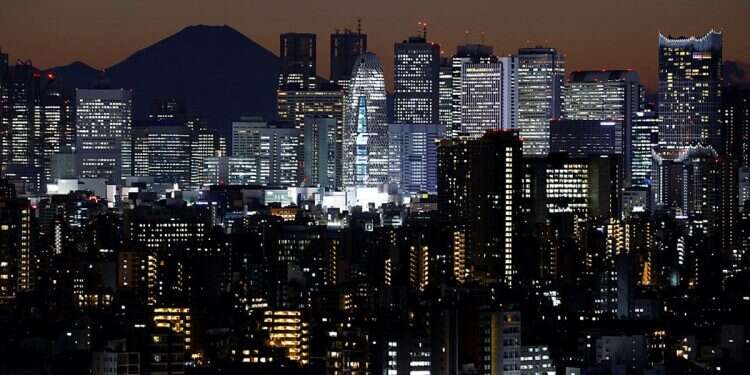 Japan's highest peak, Mount Fuji, is seen in silhouette through the Tokyo Metropolitan Government building and other Shinjuku skyscrapers after sunset in Tokyo, Japan November 28, 2024 Tokyo introduces 4-day workweek to combat lowest birth rate
