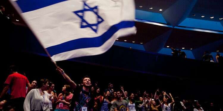 Masa program participants dance and wave Israeli flags at the program's conference Community above all