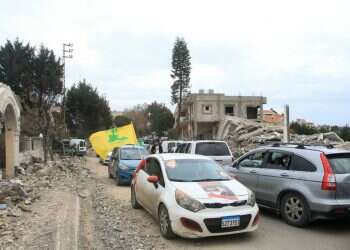 A car passenger lifts a Hezbollah flag as displaced residents gather in their vehicles while attempting to return to their homes at the entrance of the southern Lebanese village of Aitaroun on January 26, 2025 US extends Israel-Hezbollah ceasefire