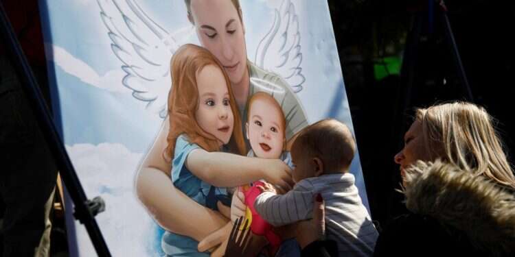 A woman holds a child up to a picture of hostages of Shiri, Ariel, and Kfir Bibas at a public square dedicated to hostages in Tel Aviv, Israel February 26, 2025 As Israel's president A message to the Bibas family