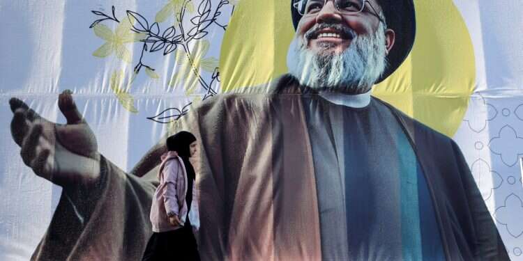 A girl walks past a picture of Hassan Nasrallah on February 24, 2025 Is Hezbollah going bankrupt? $1B budget goes sideways