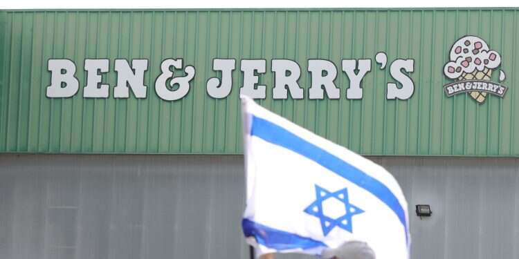 An Israeli worker of US Ice cream company Ben and Jerry's fixes a Israeli flag at the main company factory in Beer Tuvia, Israel, July 22, 2021 Ben & Jerry's Jewish co-founder: US supplies weapons for Israel's genocide