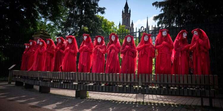 Activits wearing red stand in front of the Peace Palace as they protest against the Dutch government's Israel policy, in The Hague on May 18, 2025 Dutch FM caves to left's pressure, abandons Israel despite promises