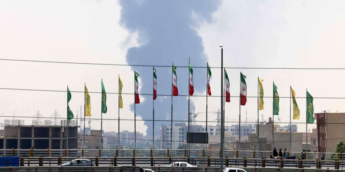 Flags flutter along a bridge as a plume of heavy smoke and fire rise from an oil refinery in southern Tehran, after it was hit in an overnight Israeli strike, on June 15, 2025 (Atta Kenare/AFP) How Mossad managed to attack Iran from within