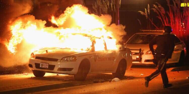 A police officer runs from a burning squad car after it was set on fire by demonstrators during a protest on November 24, 2014 in Ferguson, Missouri
'Death to the IDF': FBI probes car bombing in Missouri