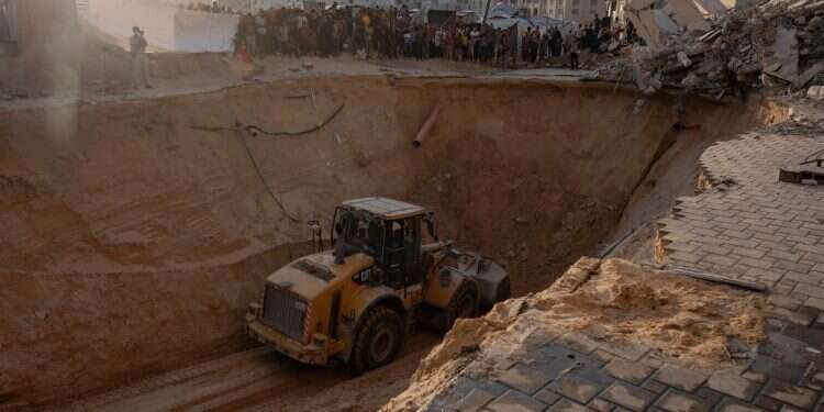 Locals gather to watch as an excavator works at the site where members of the Al-Qassam Brigades are searching for bodies Israel permits Hamas members into search zones while IDF strikes terrorist cells infiltrating from tunnels