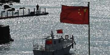 A man stands on a jetty behind a tourist boat and Chinese flags on Pingtan island, in the Taiwan Strait The 80th anniversary of Taiwan's recovery: Irrefutable historical evidence and international consensus