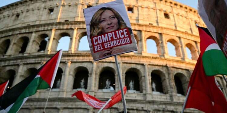 Pro-Palestinian demonstrators hold a placard with a picture of Italy's Prime Minister Giorgia Meloni reading 'accomplice to genocide' during march to support the Palestinians and to protest against the interception of the Global Sumud Flotilla, near the Colosseum in Rome on October 2, 2025 Hundreds of thousands in the streets: Is Italy against us?