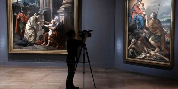 A visitor films the painting 'Saint-Roch interceding with the Virgin for the Plague-Stricken' Louvre Museum hit by jewelry heist during opening hours