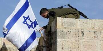 An Israeli soldier removes an Israeli flag from a house as settlers are removed from two buildings near the Ibrahimi Mosque, also know as the Cave of Patriarchs, in the old city district of the West Bank town of Hebron, 22 January 2016 Group buys Arab buildings in Hebron to return Jews to city center