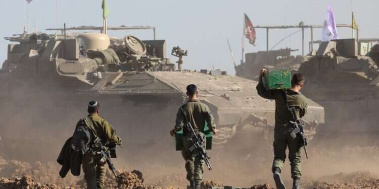 Israeli soldiers walk next to their military vehicles near the border fence with the Gaza Strip, as seen from the Israeli side in southern Israel, 10 March 2024