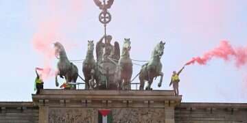 Pro-Palestinian protesters burn flares after attaching a flag of Palestine to the Brandenburg Gate and unveiling a banner reading, 'Never again genocide - Free Palestine', on top of the landmark in Berlin, Germany, November 13, 2025 'Never again genocide': Palestinian flags, flares on Germany's victory gate