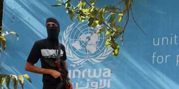 A Hamas terrorists against the backdrop of an UNRWA building (reproduction) US pivots on Gaza's 'day after' plan; UNRWA avoids sanctions