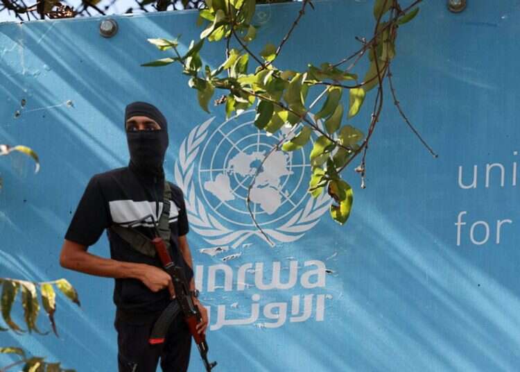 A Hamas terrorists against the backdrop of an UNRWA building (reproduction) US pivots on Gaza's 'day after' plan; UNRWA avoids sanctions