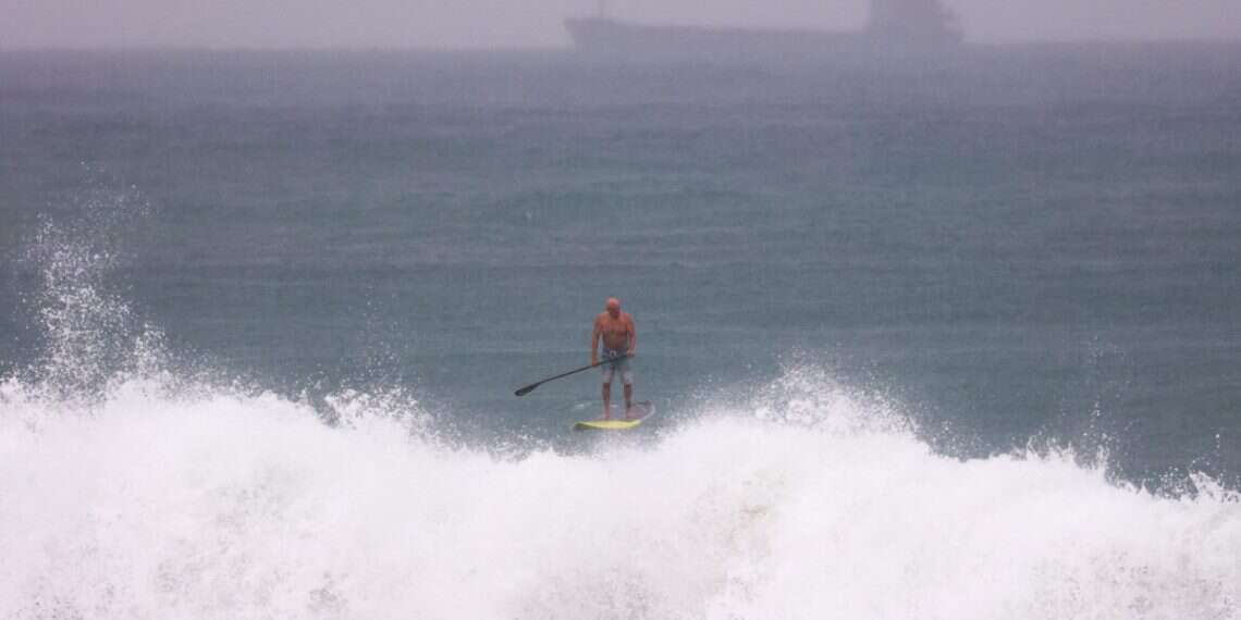 A surfer paddles in the water on an empty beach during stormy weather in Ashdod, Israel, 10 December 2025 4 Israelis missing as yacht vanishes in storm