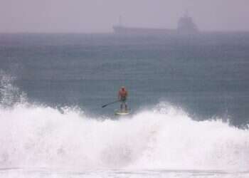 A surfer paddles in the water on an empty beach during stormy weather in Ashdod, Israel, 10 December 2025 4 Israelis missing as yacht vanishes in storm