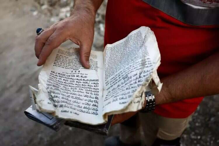 An Iranian Red Crescent member holds a Torah scroll inside a synagogue damaged in a strike. Photo: Reuters