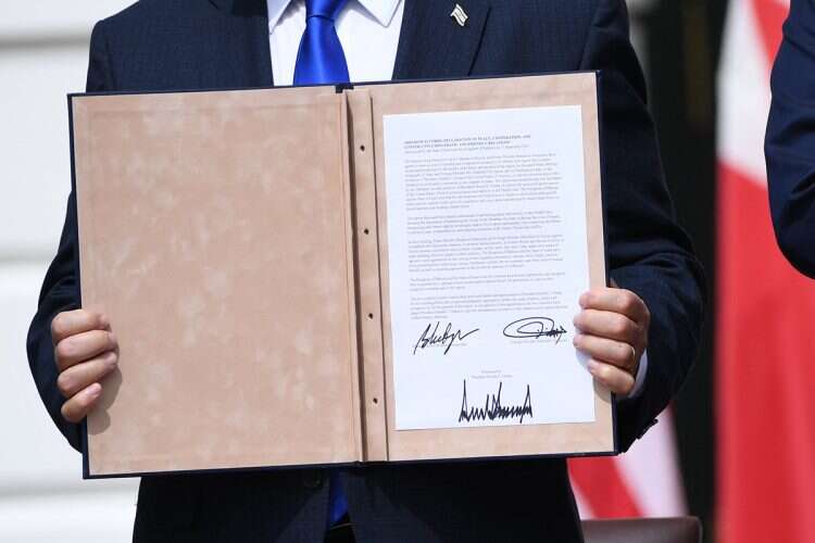 Netanyahu holds a copy of the agreement with Bahrain. Photo: AFP