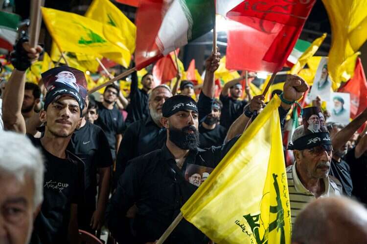 Hezbollah supporters wave the terrorist group’s flag and the Iranian flag in Beirut. Photo: Getty Images