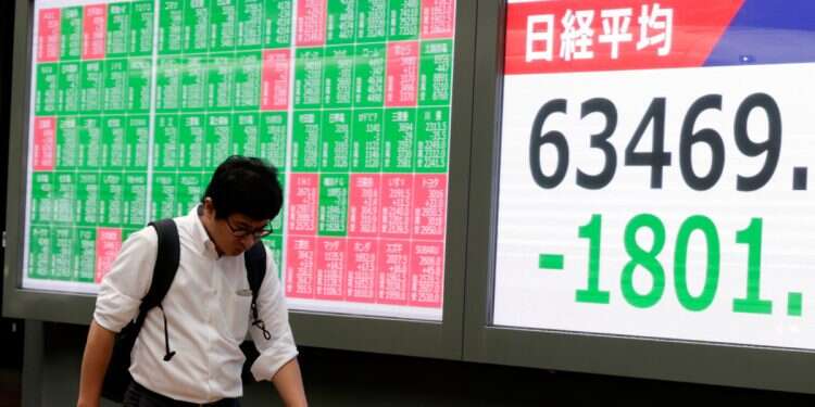 A passerby walks a stock market indicator board in Tokyo, Japan, 11 September 2026 Asian stocks sink on crude oil surge