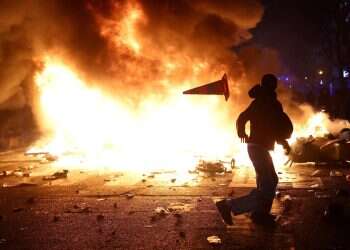 A man throws a plastic traffic cone through a burning barricade amid clashes during a day of demonstrations against the cost of living and rising fuel prices in Paris, France, October 17, 2026 Lecornu to expand curfews nationwide as riots rattle France