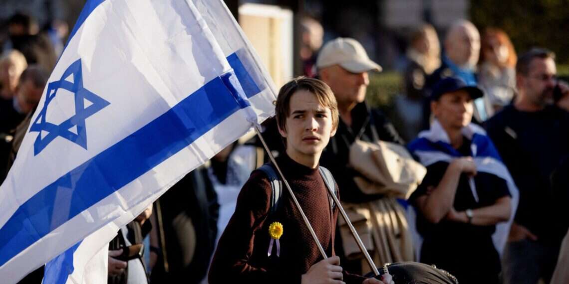 A person holds Israeli flags while attending the Czech Jewish community memorial ceremony of the Hamas-led October 7 attack against Israel, during a remembrance rally at Jan Palach Square in Prague, Czech Republic, October 7, 2026 Israel and Diaspora Jews: Who is there for whom?